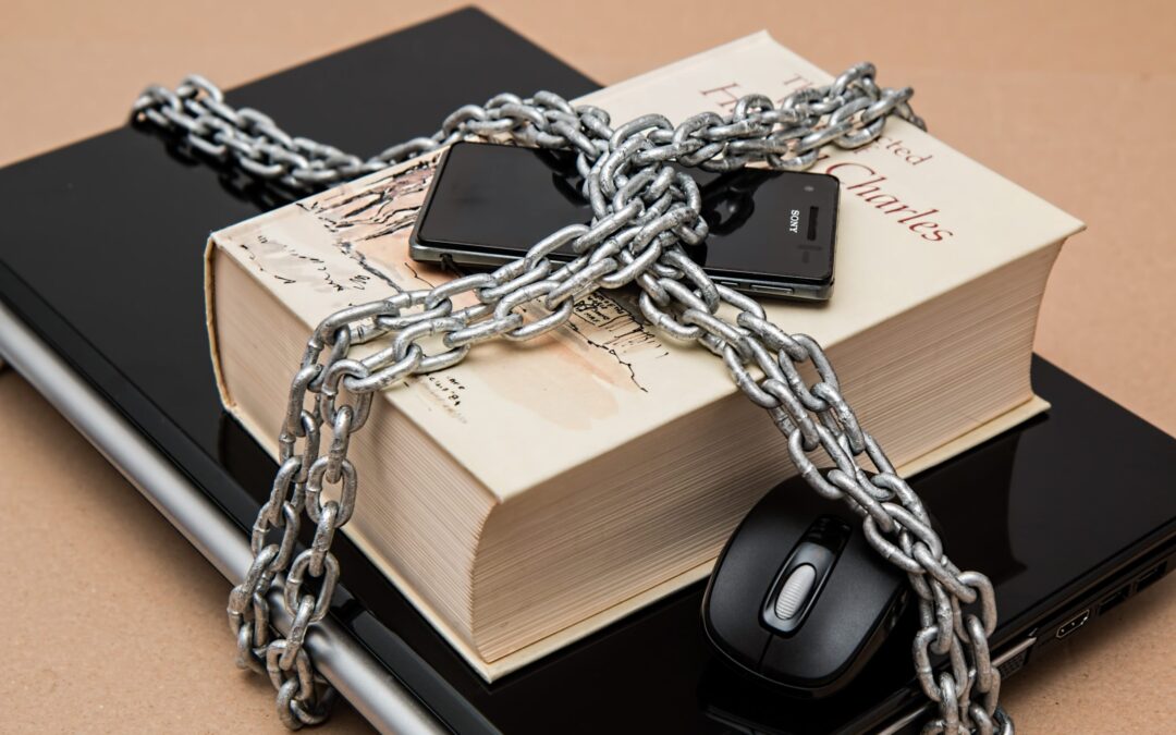 phone, book, laptop and computer mouse wrapped in chains