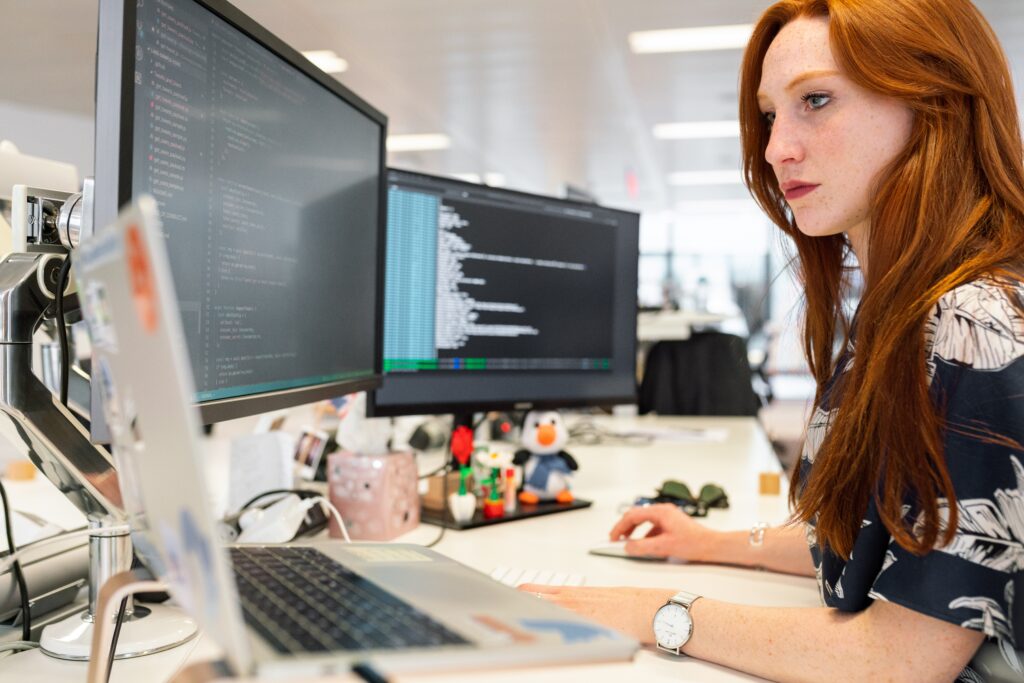 a woman is looking at three monitors